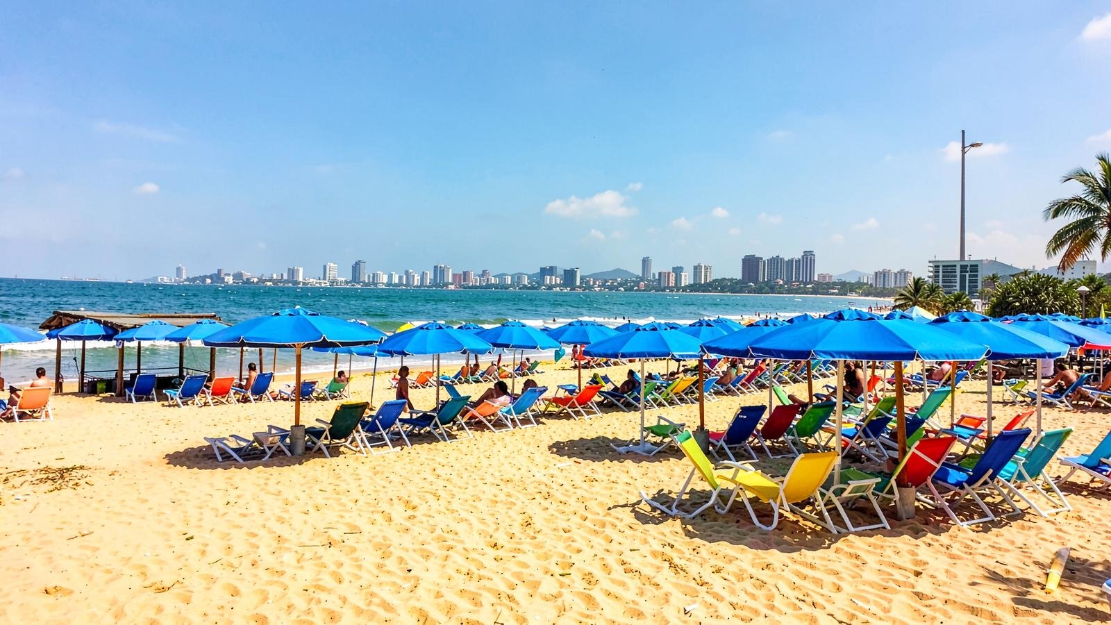 Quiosque de praia com ombrelones e cadeiras coloridas na areia